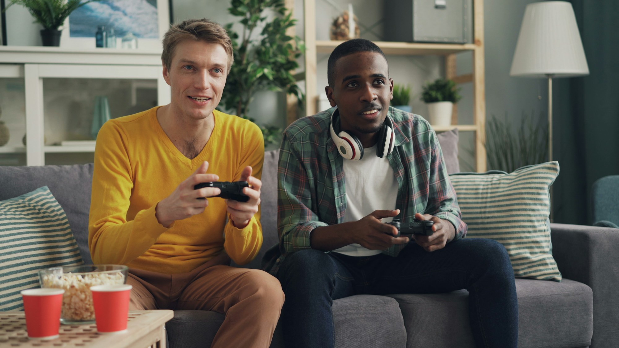 Friends on a couch holding game controllers