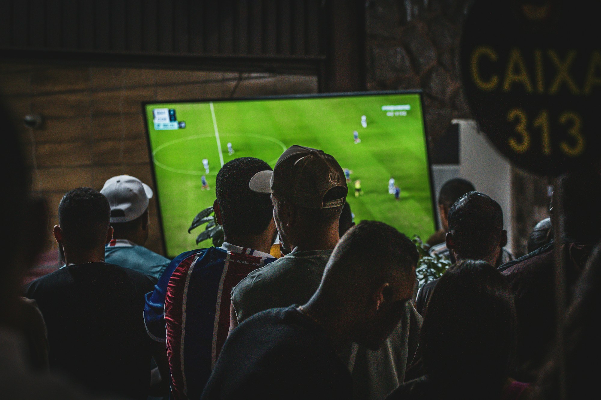 Group of friends watching a game on a big screen in a dark room